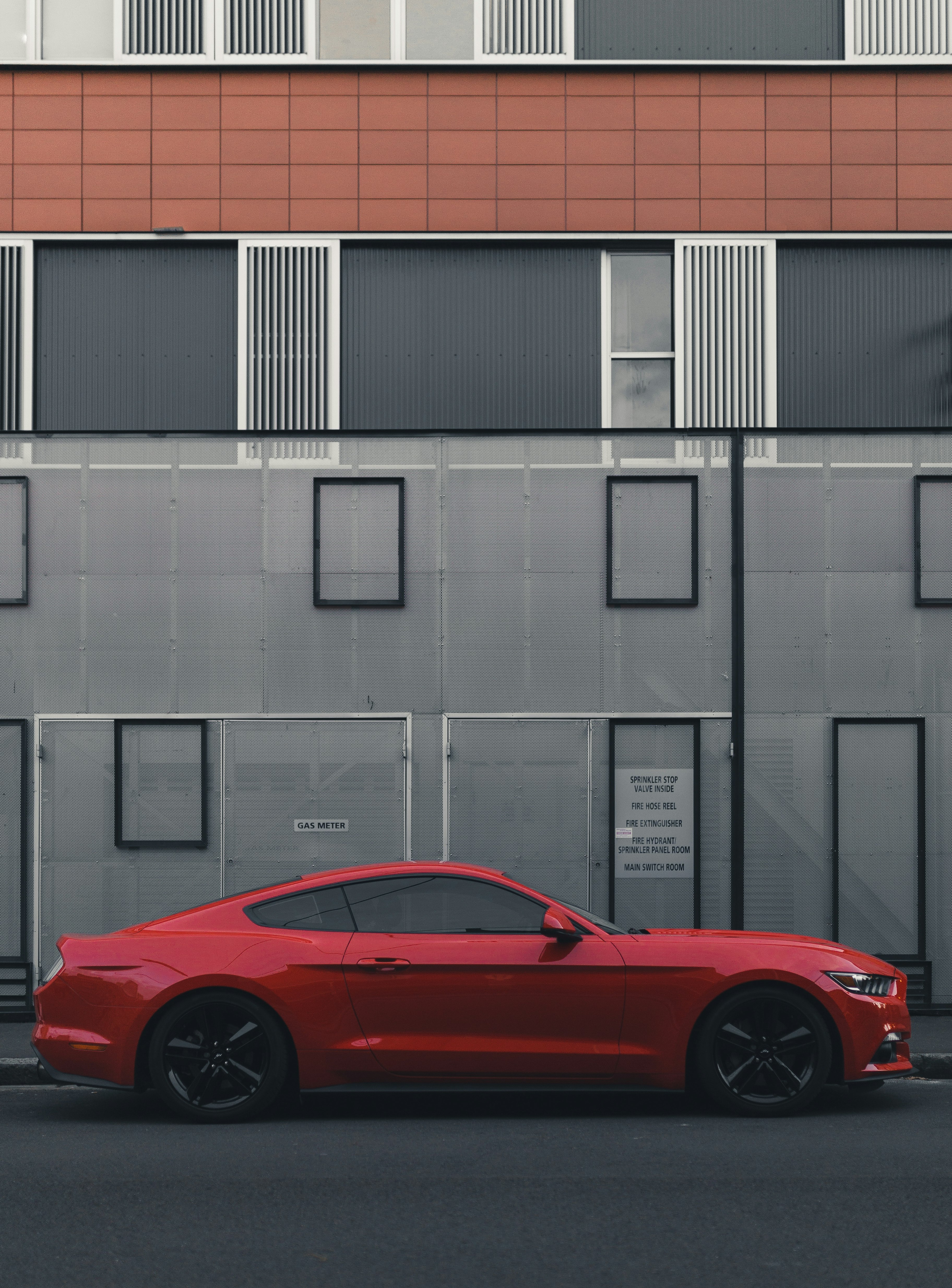 red Ford Mustang coupe parked beside the building